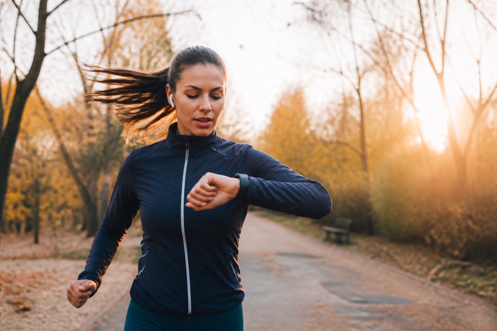 Woman running at sunrise checking her health smartwatch